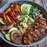 Golden pan-fried chicken sits atop a Paprika Roasted Vegetable Quinoa Bowl with creamy avocado and lemon salad.