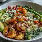 A close-up of the Rainbow Vegetable Detox Bowl shows bright red cabbage, green broccoli, and pink shrimp nestled on fluffy quinoa with creamy avocado.