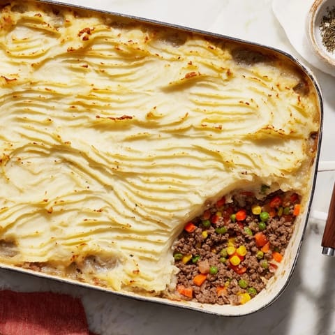 A rustic casserole dish of homemade Shepherd's Pie with hearty beef filling and cheesy potato topping.