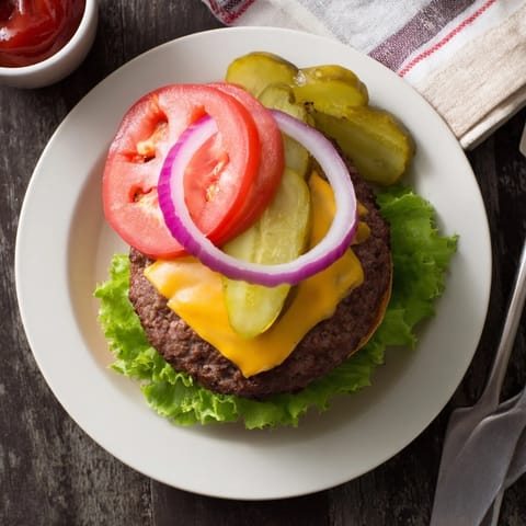 A stacked Hamburgers on a toasted bun with condiments, served alongside golden french fries on a wooden board for a casual dinner.