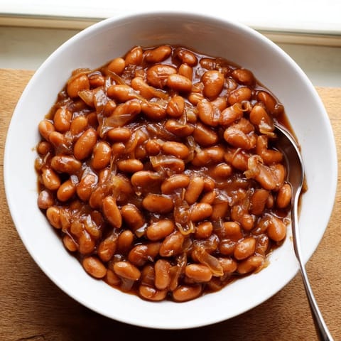 Golden-brown Baked Beans bubbling in a Dutch oven, featuring a thick, molasses-infused sauce ready to be served with barbecue.