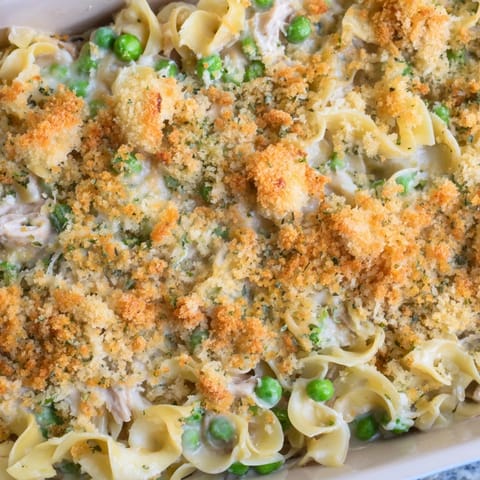 A close-up of creamy Tuna Casserole served fresh from the baking dish, garnished with fresh parsley.
