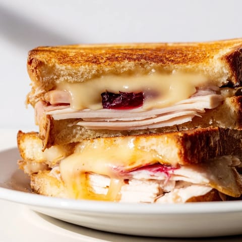 A close-up of the Smoked Turkey Grilled Cheese with melted cheese oozing from the warm, crispy sandwich.  
