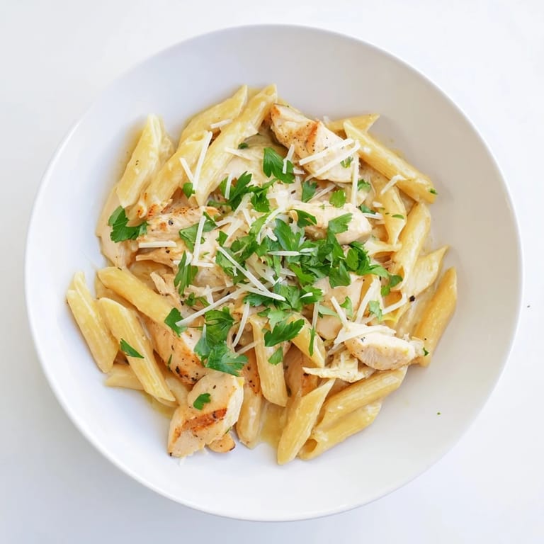 Heaping bowl of Roasted Garlic Chicken Penne, featuring juicy chicken, pasta, and a rich, aromatic cream sauce.