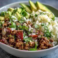 A finished Low Carb Burrito Bowl topped with avocado, sour cream, and cilantro.