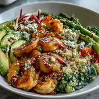 A close-up of the Rainbow Vegetable Detox Bowl shows bright red cabbage, green broccoli, and pink shrimp nestled on fluffy quinoa with creamy avocado.