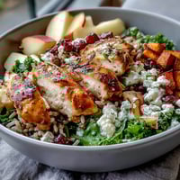 Bright roasted sweet potatoes and tender sliced chicken rest on massaged kale with wild rice, diced apple, sliced almonds, crumbled goat cheese, and a balsamic drizzle.