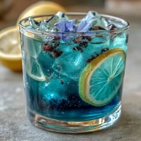 Vibrant butterfly pea flower lemonade changing from blue to purple when lemon juice is added, served over ice with lemon slices.